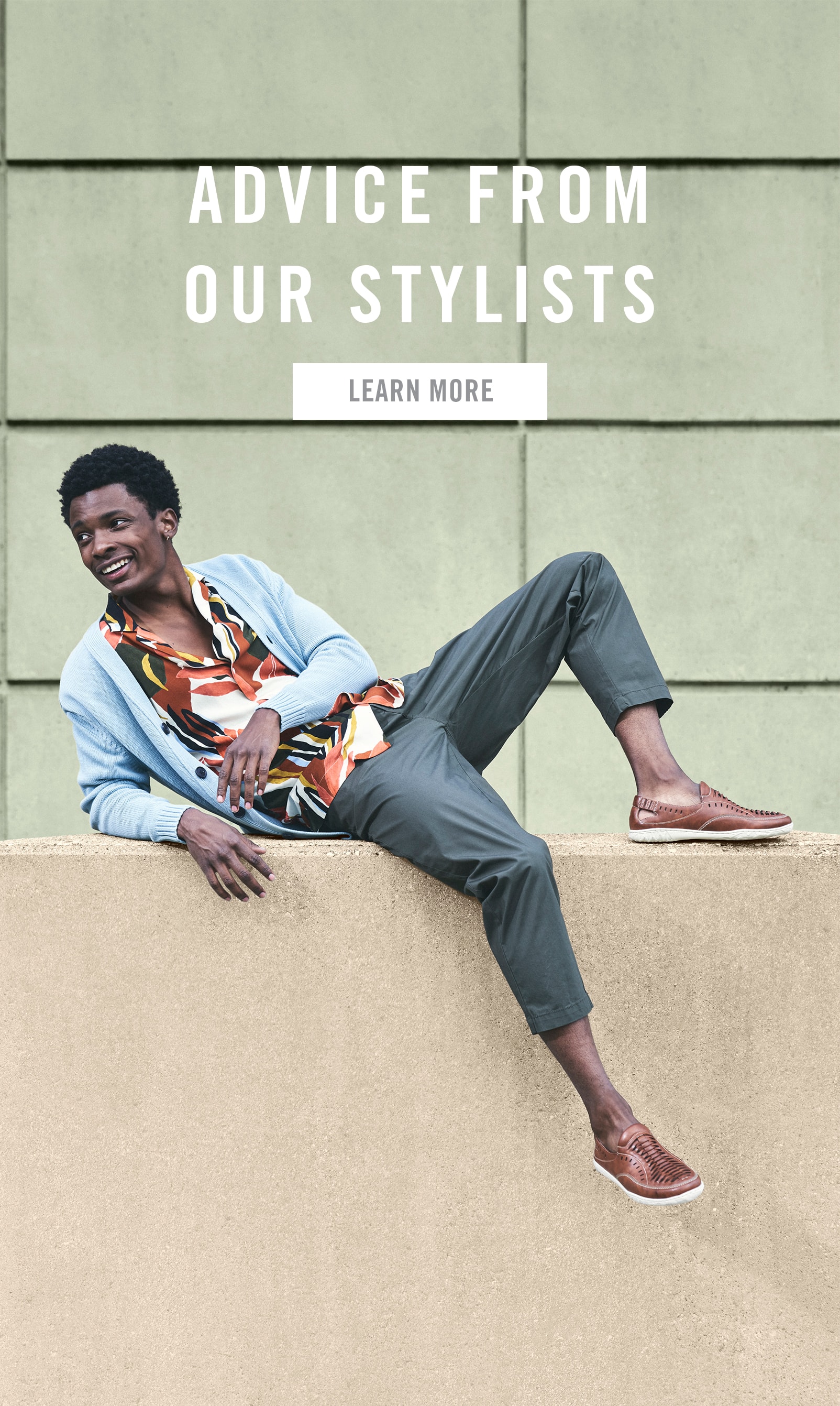 Men's Suits category. The image features a model laying down, wearing the Ibiza Woven Vamp Moc Toe Slip On in Sienna. Click for advice from our stylists. 
