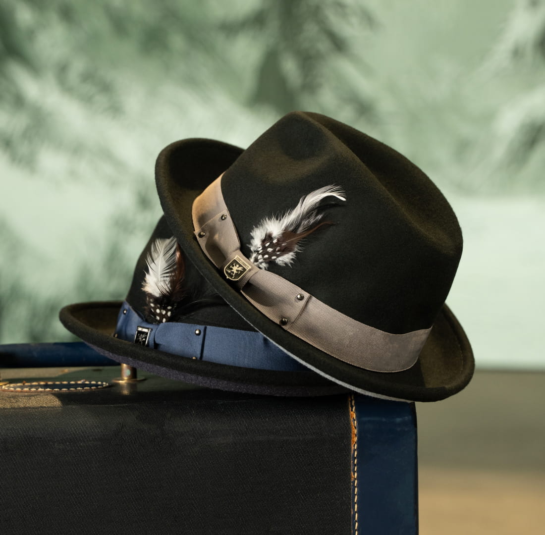 Shop Stacy Adams hats featuring 2 styles on top of a vintage suitcase.
