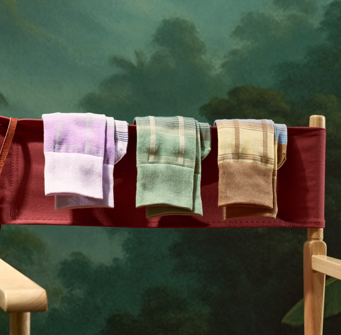 Shop Stacy Adams socks featuring 3 plaid styles on a red folding chair.