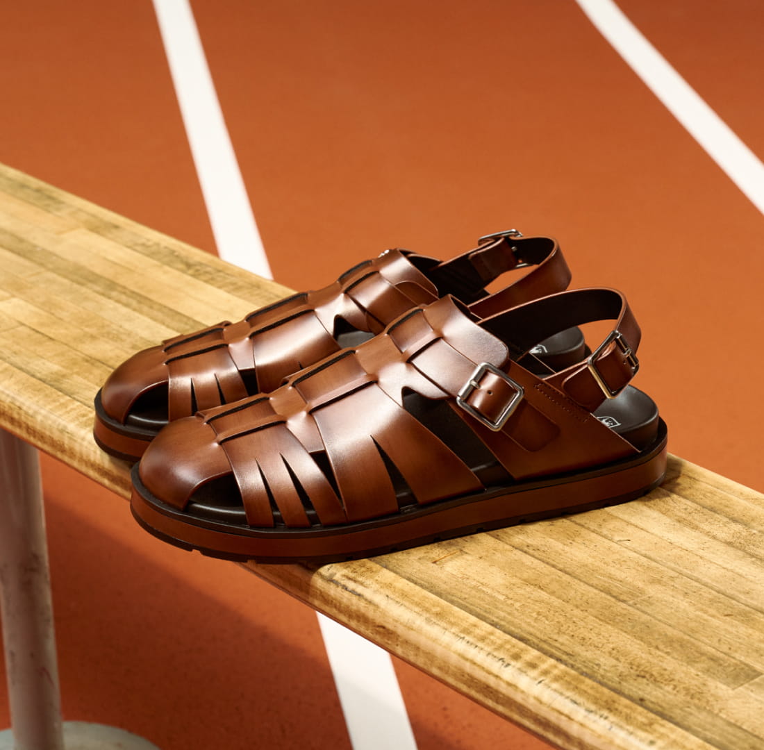 Shop Stacy Adams sandals featuring the Largo on a bench next to a pickleball court.