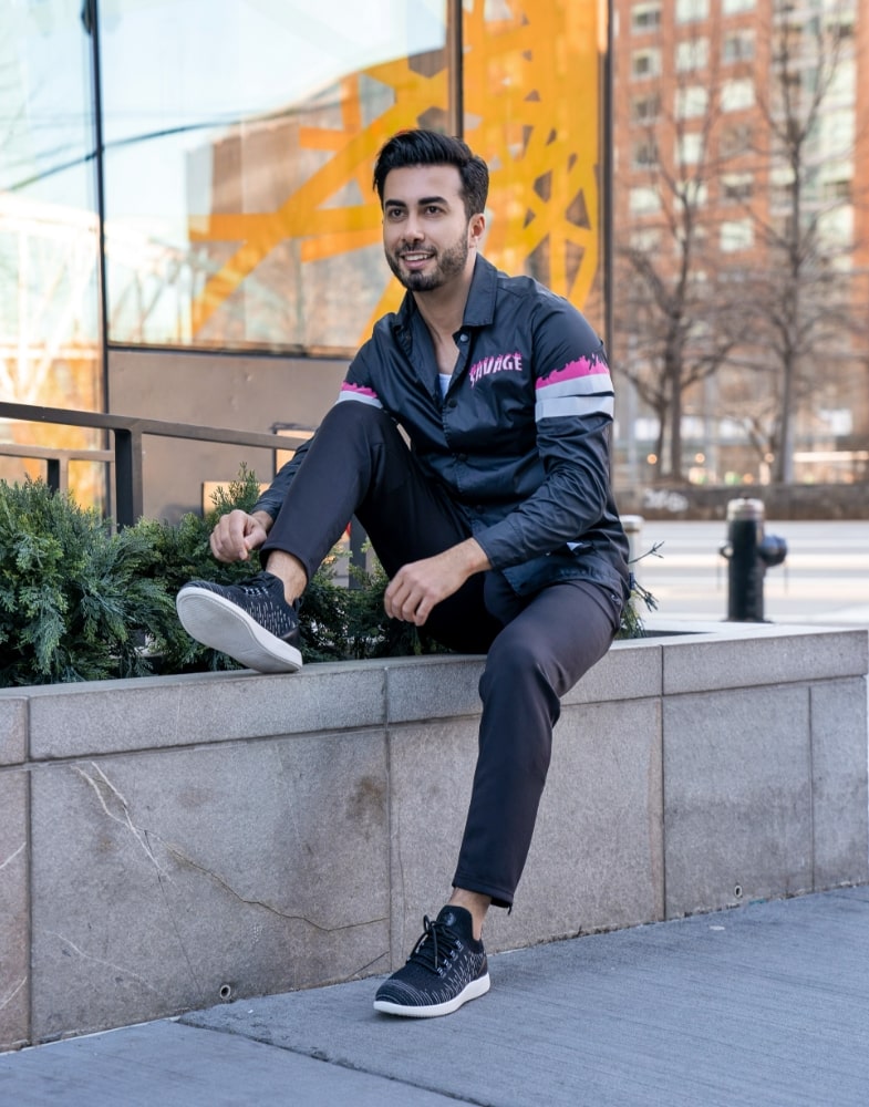 Image of social media influencer Mark Bay sitting on a ledge outside while wearing the Brio Knit Mid Lace Up in Black.