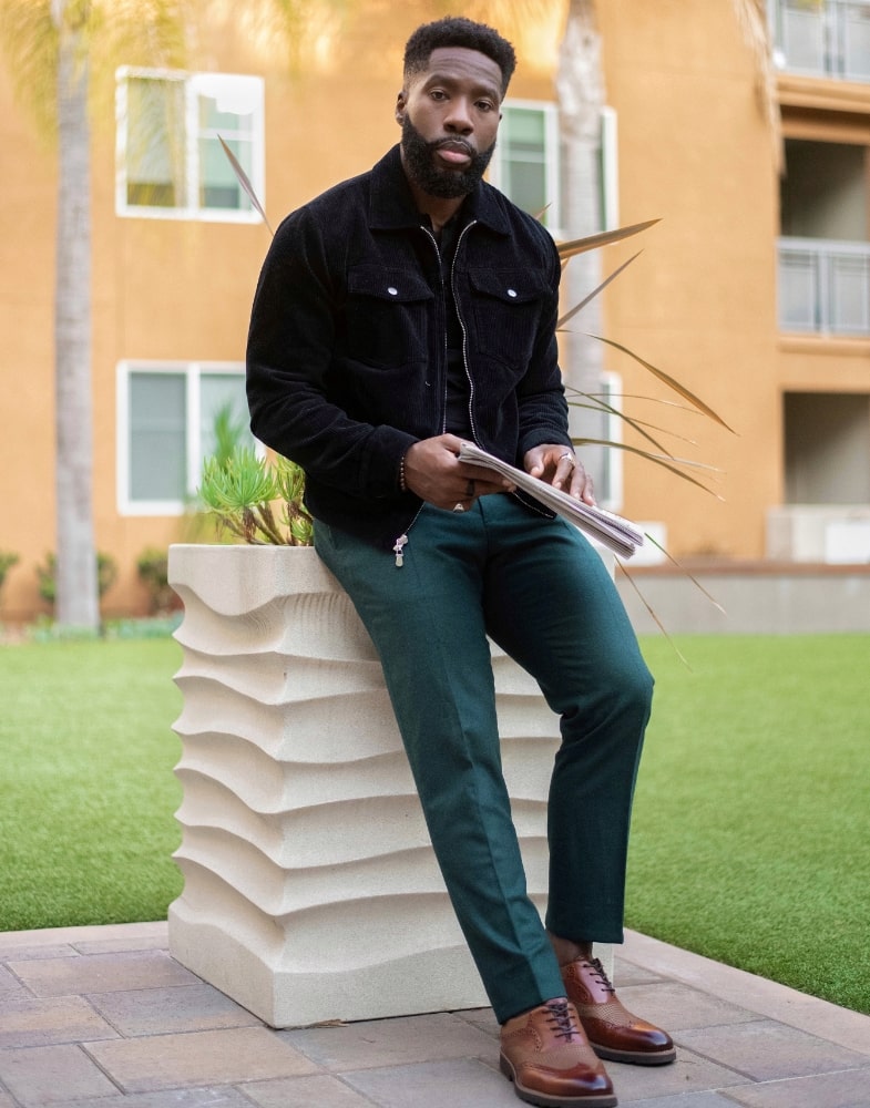 Image of social media influencer East Angles leaning up against a piller outside while wearing the Callan Wingtip Oxford in Cognac.