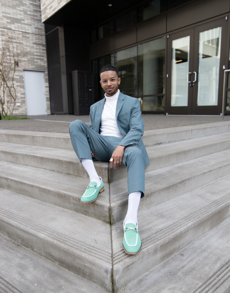 Image of social media influencer Christopher Chin sitting on steps outside while wearing the Colbin Moc Toe Ornament Strap Slip On in Green Aqua.