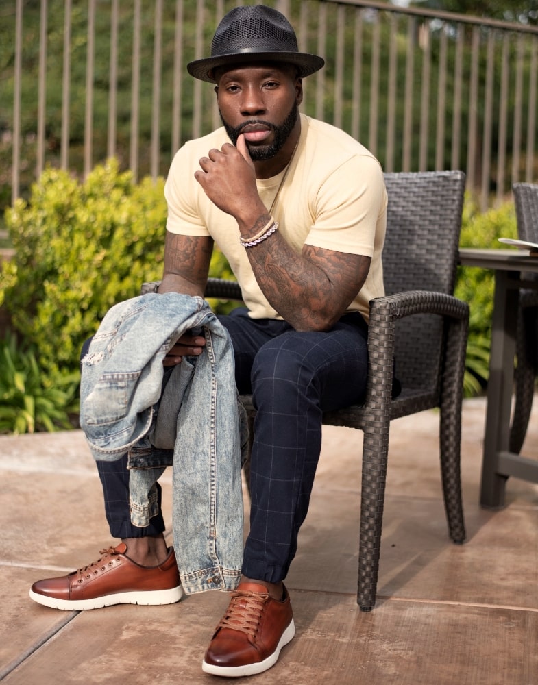 Image of social media influencer East Angles sitting down wearing the Hawkins Cap Toe Lace Up in Cognac while in Huntington Beach, California.
