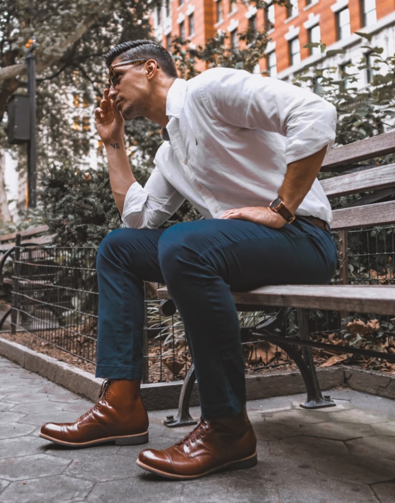 Image of social media influencer Mark from the duo "The NYC Couple" wearing the Madison Cap Toe Lace Boot in Cognac on a park bench.