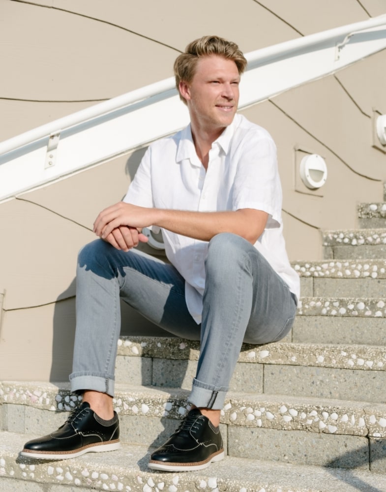 Image of social media influencer Drew Mellon sitting on steps outside in the Synergy Wingtip Oxford in Black.
