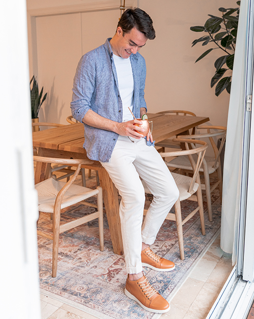 Image of social media influencer Alessandro Pontes standing against a table in the Harlow Cap Toe Mid Lace Up in Natural.