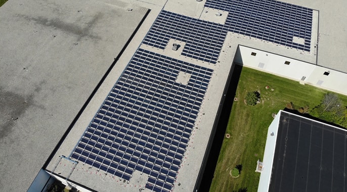 The featured image is an aerial view of a building with rooftop solar panels. 