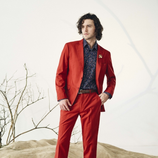 "Master The Differences Between A Blazer, Sport Coat, And Suit Jacket." The featured image is a model wearing a red suit.
