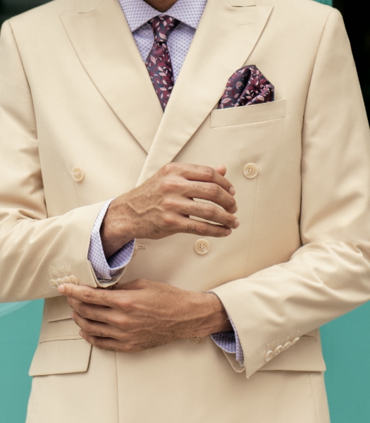 The featured image is of a model wearing a cream suit with a dark red patterned tie and pocket square. 