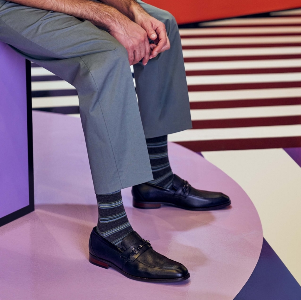 "Fashion For Men: How To Make A Statement With Your Outfit." The featured image is a model wearing black slip ons on a purple background.