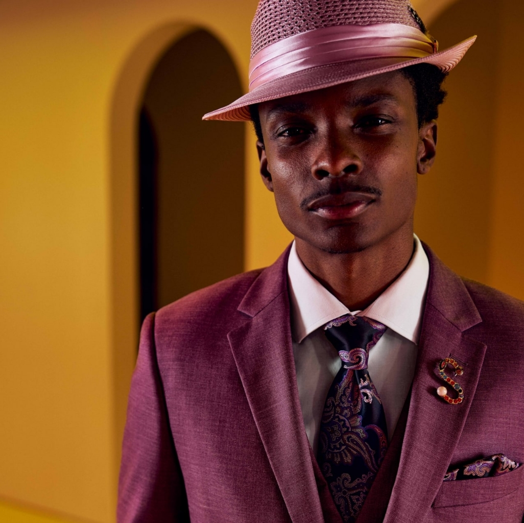 "Men’s Accessories that Complete your Look." The featured image is a model wearing a purple suit and purple fedora with an orange background.