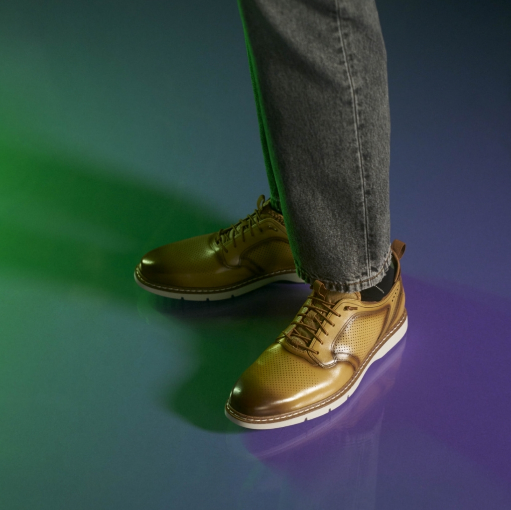 "Sneakers, Loafers, and Casual Shoes For Men That Add Style to Your Downtime." The featured image is of a model wearing a pair of light brown oxfords on a purple background.