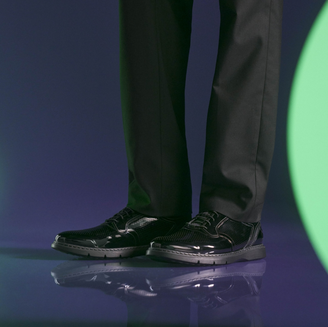 "In The World Of Men’s Casual Shoes, Sneakers Take Center Stage." The featured image is of a model wearing the Sync in black on a dark purple background.