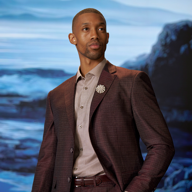 "Master The Differences Between A Blazer, Sport Coat, And Suit Jacket." The featured image is a model wearing a burgandy plaid Stacy Adams suit, plaid dress shirt, and burgandy belt while standing in front of a blue background, looking to the side.