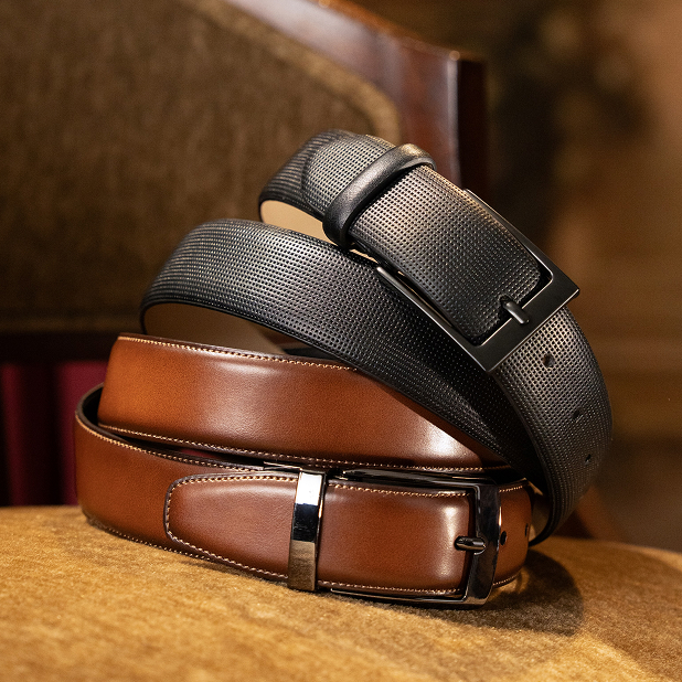 "Men’s Belts: The Perfect Finishing Touch." The featured products are two Stacy Adams belts stacked on top of each other on a beige velvet chair, one in cognac and one in black.