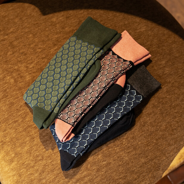 "Men’s Accessories that Complete your Look." The featured image is of a collection of Stacy Adams Colorful Hexagons Dress Socks in a variety of colors including olive green, coral, and dark blue..