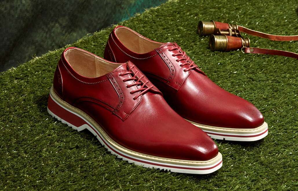 "Keeping Up With Men’s Fashion Trends As The Seasons Change." The featured image is of the Stacy Adams Barringer Plain Toe Oxford shoe in red on an astroturf floor with a painted landscape background.
