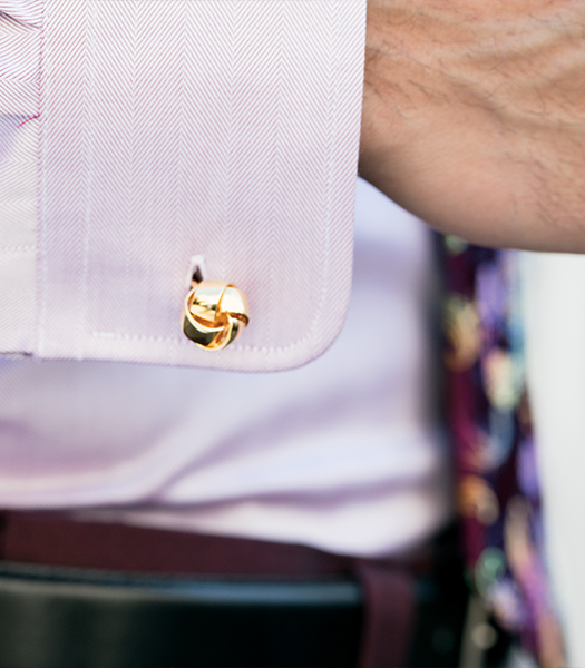 The featured image is a gold cufflink on a man's wrist.