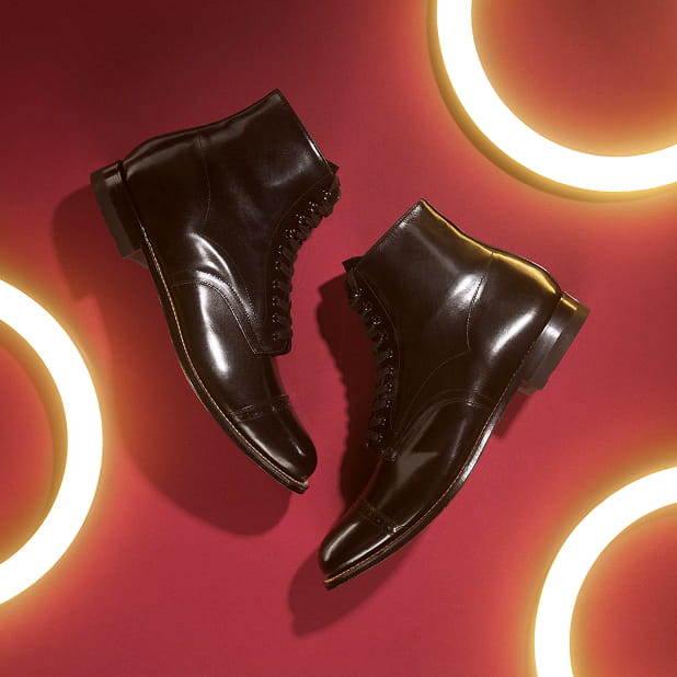"Elevate Your Style With A Pair Of Men’s Black Boots." The featured image shows the Stacy Adams Henry Cap Toe Lace Up Boots in Black against a red background with circular lights.