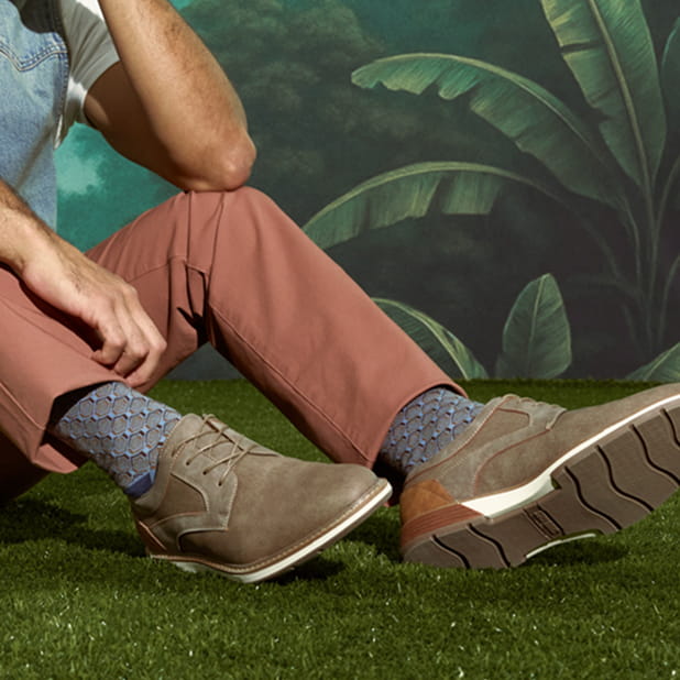 "The Best Men's Fashion Socks And How To Style Them." The featured image shows a model wearing Stacy Adams lace-up shoes and patterned socks while sitting on grass.